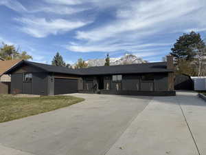 Ranch-style home featuring a garage and a front yard with mountains in background