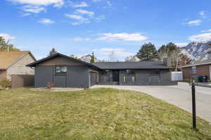 Ranch-style house with a mountain view, a front lawn, and a garage