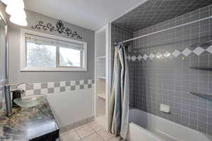 Bathroom featuring tile patterned flooring, shower / tub combo, tile walls, and sink