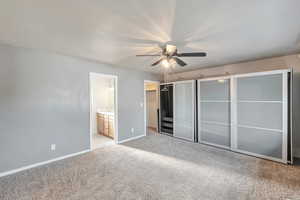 Unfurnished bedroom featuring ceiling fan, a textured ceiling, connected bathroom, light colored carpet, and a closet