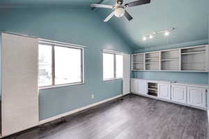 Unfurnished office featuring lofted ceiling with beams, ceiling fan, and dark wood-type flooring