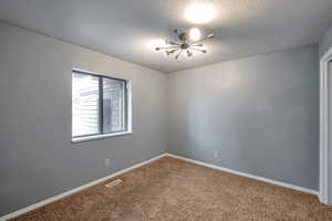 Carpeted empty room featuring a textured ceiling