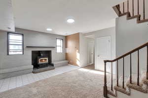 Living room featuring a wood stove, a wealth of natural light, and light tile patterned floors