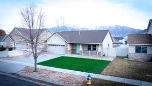 View of front of house with a mountain view, a porch, a garage, and a front yard