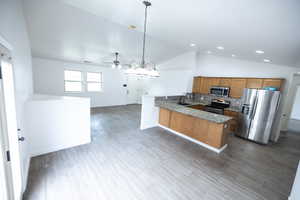 Kitchen featuring kitchen peninsula, appliances with stainless steel finishes, tile flooring, pendant lighting, and lofted ceiling