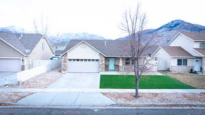 View of front facade with a mountain view, a garage, and a front lawn