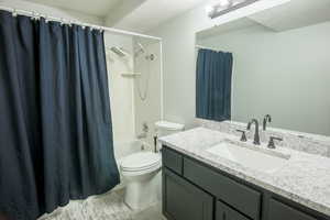 Full updated bathroom with shower / bath combination with curtain, vanity, a textured ceiling, and toilet