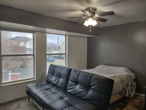 2nd Bedroom with up, ceiling fan, carpet floors, and a textured ceiling