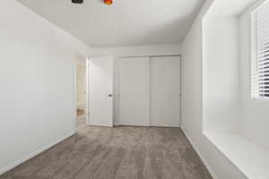 Unfurnished bedroom featuring light carpet, a textured ceiling, and a closet