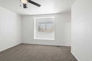 Carpeted empty room featuring ceiling fan and a textured ceiling