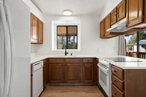 Kitchen featuring sink, white appliances, and light hardwood / wood-style flooring