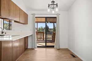 Kitchen featuring light hardwood / wood-style floors, an inviting chandelier, hanging light fixtures, and sink