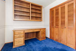 Unfurnished office featuring dark carpet and built in desk