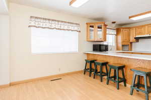 Kitchen with kitchen peninsula, a kitchen breakfast bar, cooktop, and light hardwood / wood-style flooring