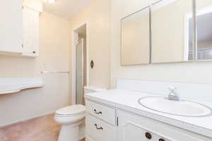 Bathroom featuring a shower, vanity, and toilet