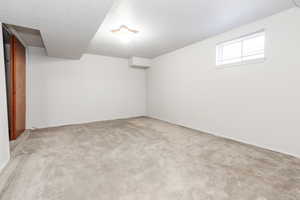 Basement featuring light colored carpet and a textured ceiling