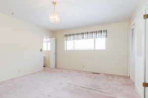 Unfurnished bedroom featuring light carpet, a closet, and an inviting chandelier