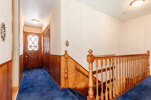 Hall with a textured ceiling and dark colored carpet