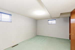 Basement with carpet flooring, a healthy amount of sunlight, and a textured ceiling