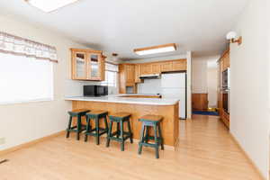 Kitchen with kitchen peninsula, a kitchen breakfast bar, light wood-type flooring, and stainless steel appliances