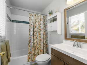 Full bathroom with vanity, toilet, a textured ceiling, and shower / tub combo with curtain