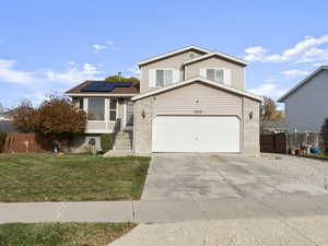 View of front of home featuring solar panels, a garage, and a front yard