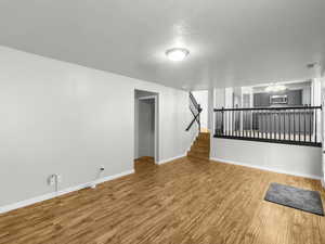 Unfurnished living room featuring hardwood / wood-style floors, a chandelier, and a textured ceiling