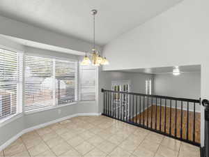 Tiled spare room featuring a chandelier