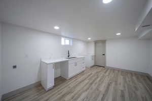 Clothes washing area featuring sink and light hardwood / wood-style flooring