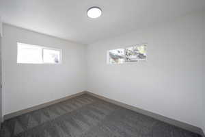 Unfurnished room with dark colored carpet and plenty of natural light