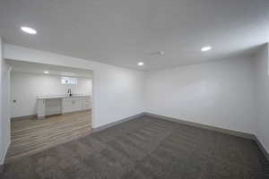 Empty room with sink, a textured ceiling, and light hardwood / wood-style flooring