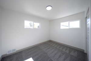 Unfurnished room featuring dark colored carpet