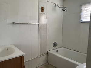 Bathroom with vanity, shower / bath combination, and wood walls