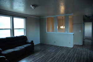 Living room featuring dark hardwood / wood-style flooring, crown molding, and a notable chandelier