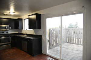 Kitchen with stainless steel appliances, dark wood-type flooring, and sink