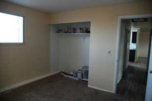 Unfurnished bedroom with dark carpet and a closet