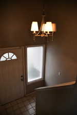 Foyer with a notable chandelier, a healthy amount of sunlight, and light tile patterned flooring