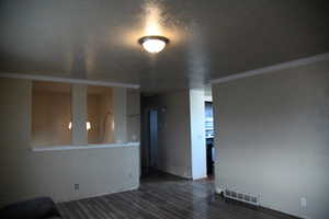 Unfurnished living room with crown molding and dark wood-type flooring