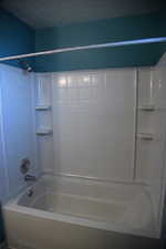 Bathroom featuring a textured ceiling and tiled shower / bath