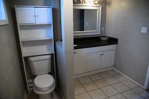 Bathroom with toilet, vanity, and tile patterned floors