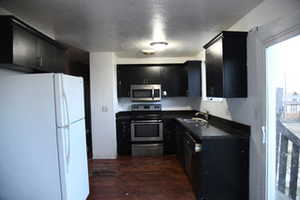 Kitchen with sink, dark hardwood / wood-style floors, and appliances with stainless steel finishes