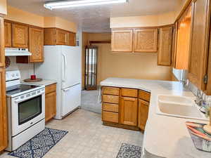 Kitchen featuring a textured ceiling, white appliances, and sink