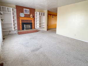 Unfurnished living room with a fireplace, a textured ceiling, and carpet floors