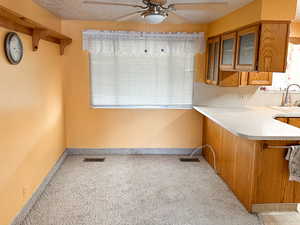 Kitchen with light carpet, kitchen peninsula, a textured ceiling, ceiling fan, and sink