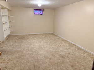 Basement with carpet flooring and a textured ceiling