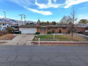 Single story home featuring a mountain view, a garage, and a front yard