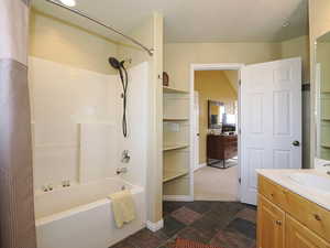 Bathroom with lofted ceiling, shower / bath combo with shower curtain, and vanity