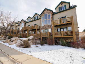 Snow covered rear of property featuring a balcony