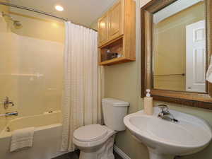 Full bathroom featuring toilet, sink, and shower / tub combo with curtain