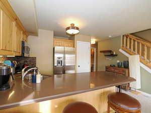 Kitchen with kitchen peninsula, appliances with stainless steel finishes, light brown cabinets, and sink